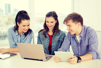 Image showing three smiling students with laptop and tablet pc