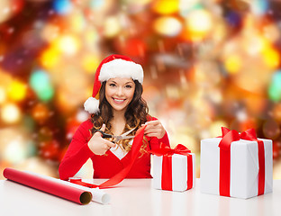 Image showing smiling woman in santa helper hat packing gift box