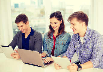 Image showing three smiling students with laptop and tablet pc