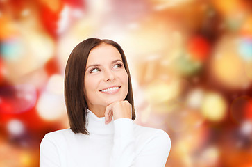 Image showing thinking and smiling woman in white sweater