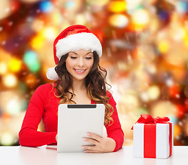 Image showing smiling woman in santa hat with gift and tablet pc