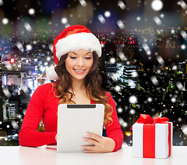 Image showing smiling woman in santa hat with gift and tablet pc