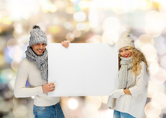 Image showing smiling couple in winter clothes with blank board