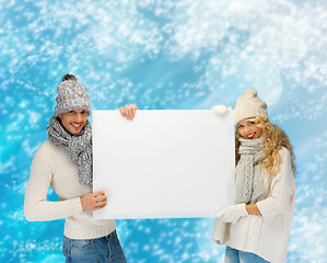 Image showing smiling couple in winter clothes with blank board