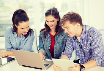 Image showing three smiling students with laptop and tablet pc