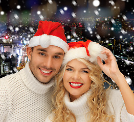 Image showing smiiling couple in sweaters and santa helper hats