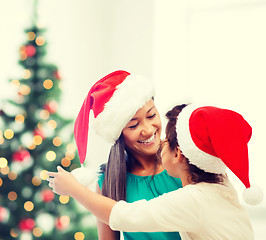 Image showing hugging mother and daughter in santa helper hats