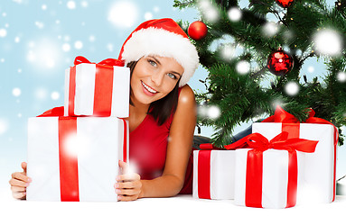 Image showing smiling woman in santa helper hat with gift boxes