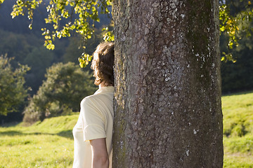 Image showing Woman leaning at a tree at sunset