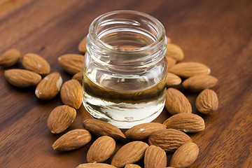Image showing Almond oil with nuts on wooden background
