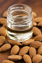 Image showing Almond oil with nuts on wooden background