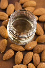 Image showing Almond oil with nuts on wooden background