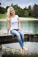 Image showing Blond woman sitting on a jetty