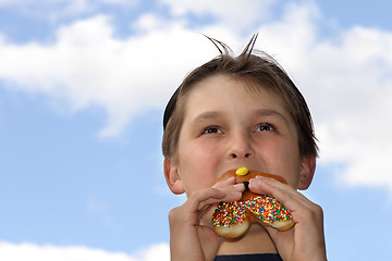 Image showing Boy biting into donut