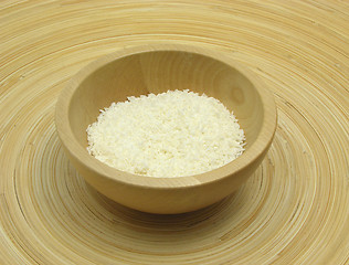 Image showing Wooden bowl with coconut flakes on bamboo plate