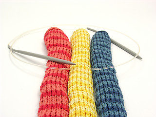 Image showing Three striped  knitting scarfs with needle on white