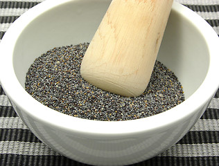 Image showing Pestling poppy seeds  in a bowl of chinaware