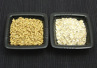 Image showing Oat and flakes in bowls of chinaware on black mat