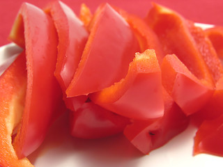Image showing Slitted red pepper on a white plate and  red placemat