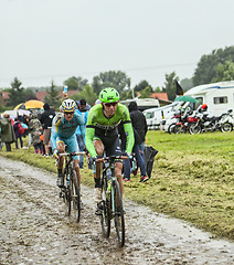 Image showing Two Cyclsits on a Cobbelstoned Road in the Rain