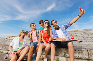 Image showing group of smiling friends with smartphone outdoors