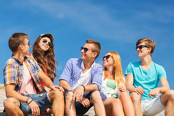 Image showing group of smiling friends sitting on city street