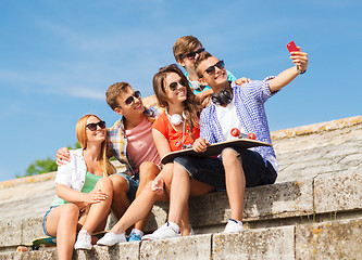 Image showing group of smiling friends with smartphone outdoors