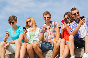 Image showing group of smiling friends with smartphones outdoors