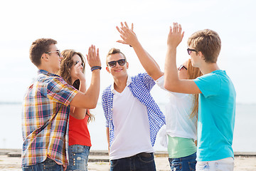 Image showing group of smiling friends making high five outdoors