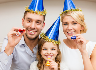 Image showing smiling family in blue hats blowing favor horns