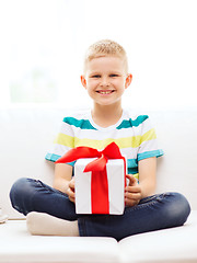 Image showing smiling little holding gift box sitting on couch