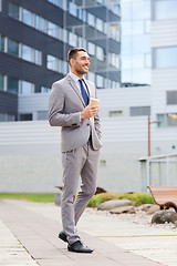 Image showing young serious businessman with paper cup outdoors