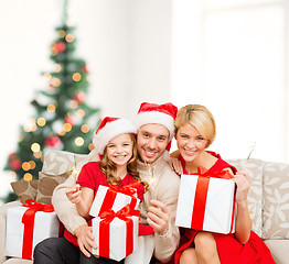 Image showing smiling family holding gift boxes and sparkles