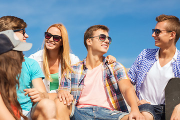 Image showing group of smiling friends sitting on city street