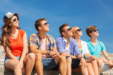 Image showing group of smiling friends sitting on city street