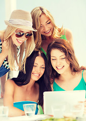 Image showing smiling girls looking at tablet pc in cafe