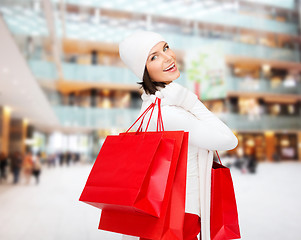 Image showing smiling young woman with red shopping bags