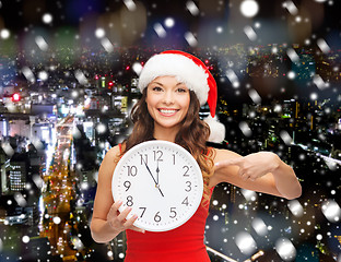 Image showing smiling woman in santa helper hat with clock