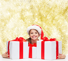 Image showing smiling girl in santa helper hat with gift boxes