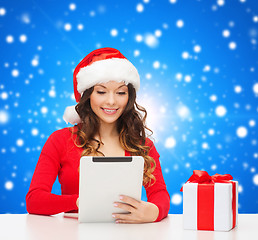 Image showing smiling woman in santa hat with gift and tablet pc