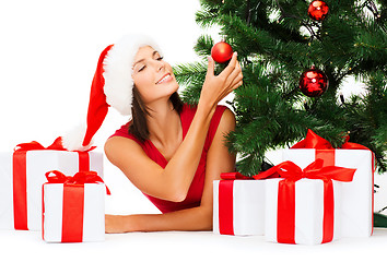 Image showing smiling woman in santa helper hat with gift boxes