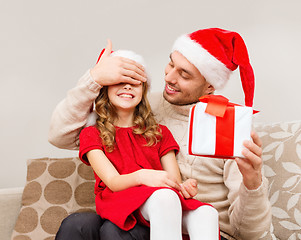 Image showing smiling father surprises daughter with gift box