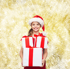 Image showing smiling little girl in santa helper hat with gifts