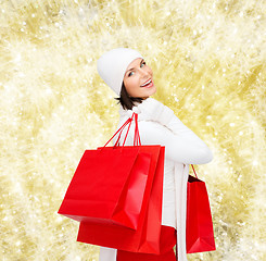 Image showing smiling young woman with red shopping bags