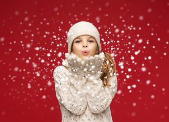 Image showing happy girl in winter clothes blowing on palms