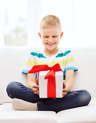 Image showing smiling little holding gift box sitting on couch