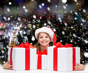 Image showing smiling girl in santa helper hat with gift boxes