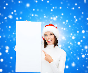 Image showing smiling young woman in santa hat with white board