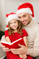 Image showing smiling father and daughter reading book