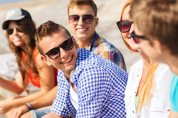 Image showing close up of smiling friends sitting on city street